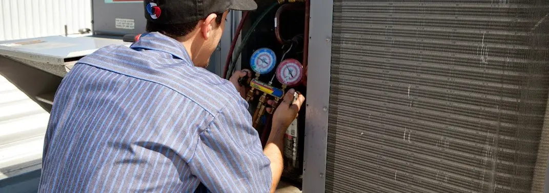 HVAC technician servicing a condenser unit in Tomball